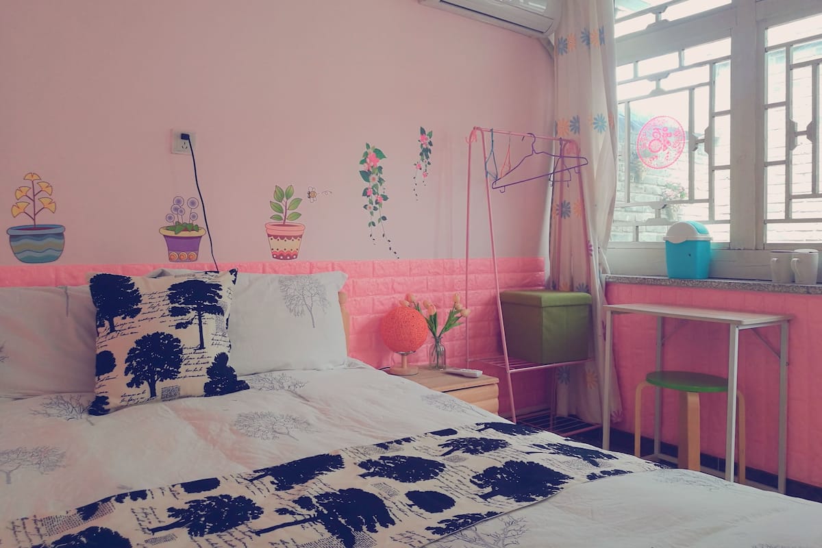 Un dormitorio con cama, una mesita de noche, un sillón colgante y una ventana con cortinas.
