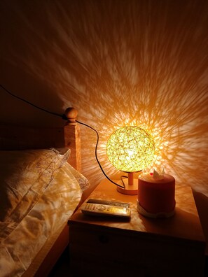 A bedside table with a globe lamp, a remote control, and a candle holder. - Beijing Badaling Great Wall Caos Hostel (Yanqing)