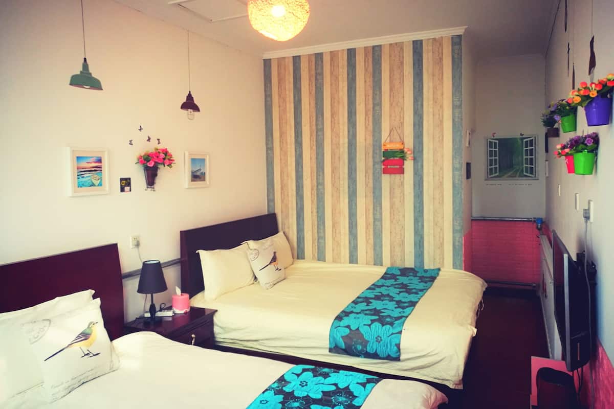 Habitación de hotel con dos camas, un pared a rayas y una lámpara colgante.