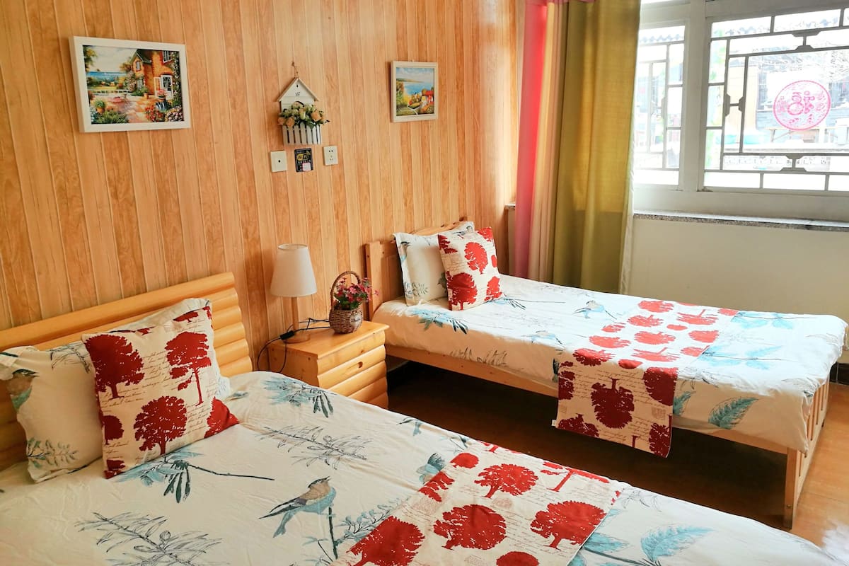 Una habitación con dos camas, paredes de madera y una ventana con cortinas.