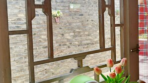 A window with a view of a brick wall and a hanging sign. - Beijing Badaling Great Wall Caos Hostel (Yanqing)