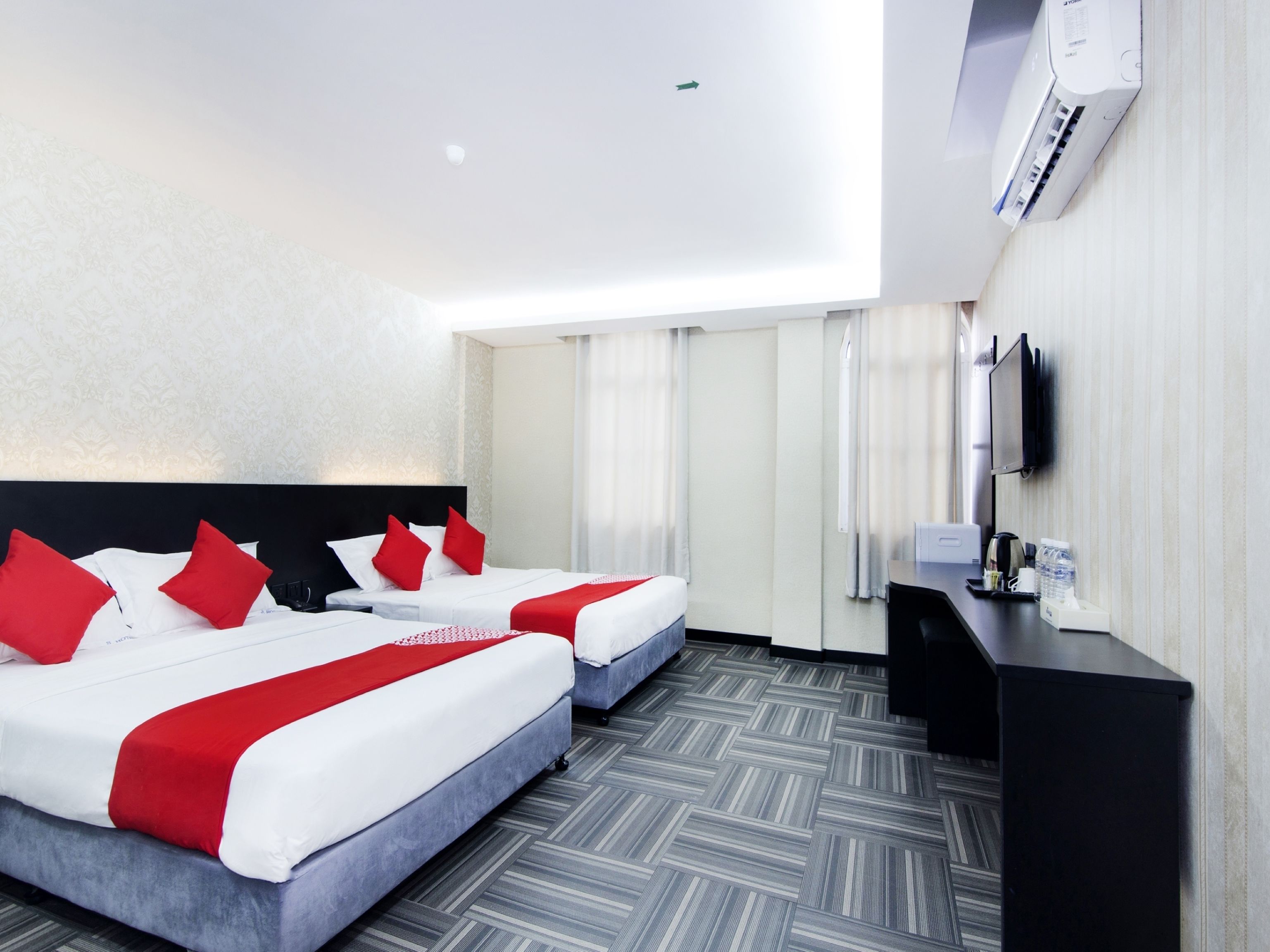 A hotel room with two beds, a desk, a flat-screen TV, and a minibar.