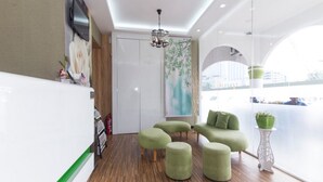 A modern living room with wooden flooring, green ottomans, a flat-screen TV, and a large window with a view of the city. - S Hotel (Seberang Jaya)