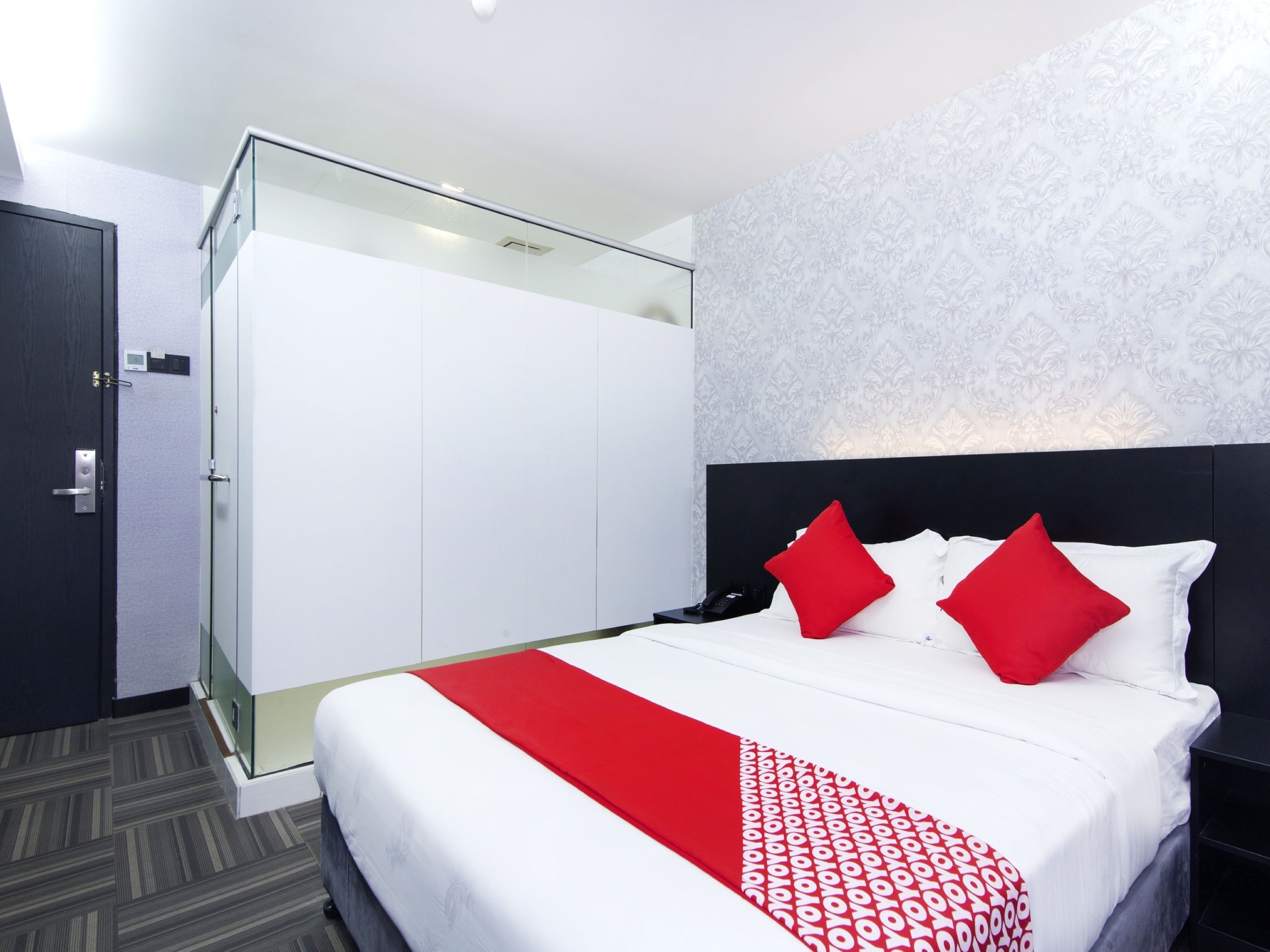 Una habitación de hotel con cama, armario y separador de vidrio.