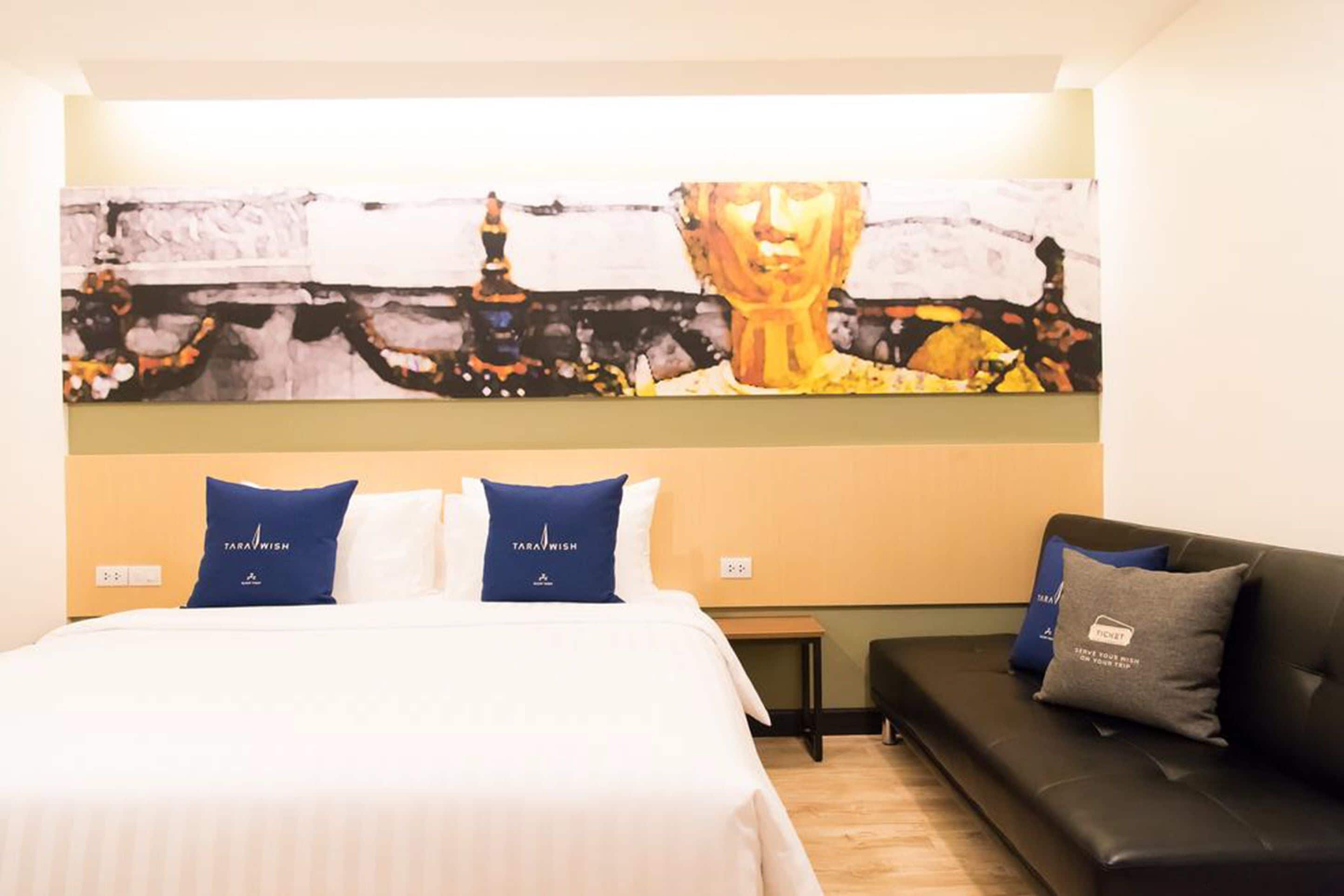 Una habitación de hotel con una cama, un sofá y un cuadro abstracto de gran tamaño en la pared.