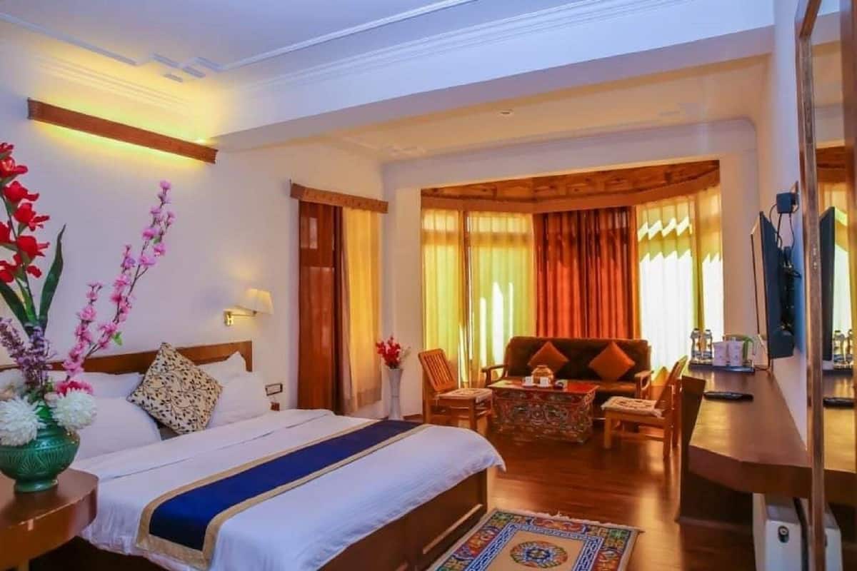 A hotel room with a large bed, a sitting area with a sofa and chairs, a small table, and a TV.
