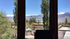 A room with a view of snow-capped mountains and a building with a flat roof. - Himalayan Retreat Karzoo (Leh)