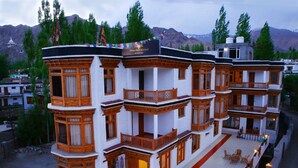 A multi-story building with traditional architecture, featuring balconies and a courtyard with outdoor seating. - Himalayan Retreat Karzoo (Leh)