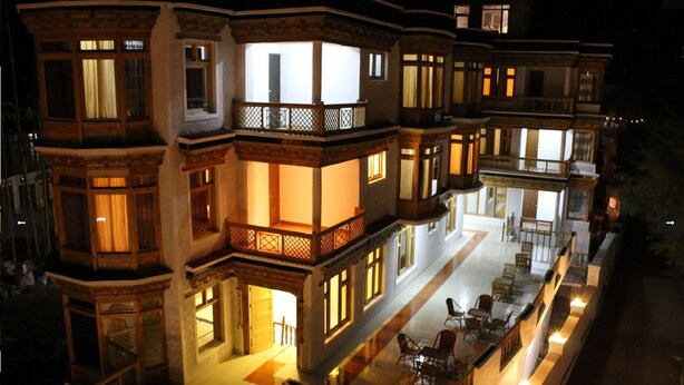 A multi-story hotel with balconies, outdoor seating, and a well-lit facade. - Himalayan Retreat Karzoo (Leh)