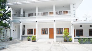 Un edificio de varios pisos con un patio central, que cuenta con balcones, plantas en macetas y una antena parabólica.