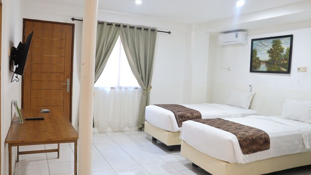 Habitación de hotel con dos camas, un escritorio de madera, una ventana con cortinas y un cuadro en la pared.