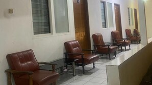 Un área de espera con filas de sillones de cuero, piso de baldosas y una escalera que conduce a un nivel superior.