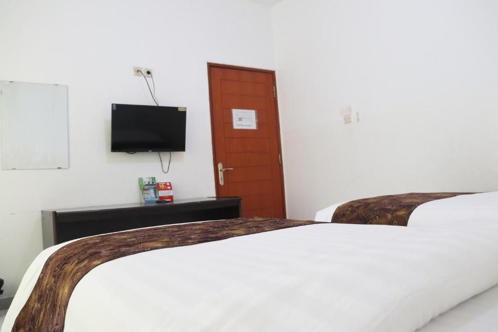 A hotel room with a bed, a television mounted on the wall, a door, and a small table with items on it.