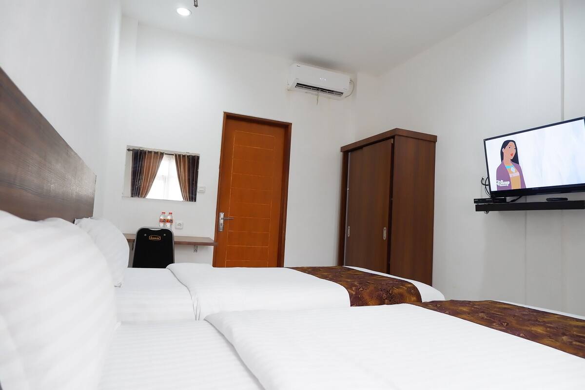 Quarto de hotel com duas camas, televisão, guarda-roupa e minibar.