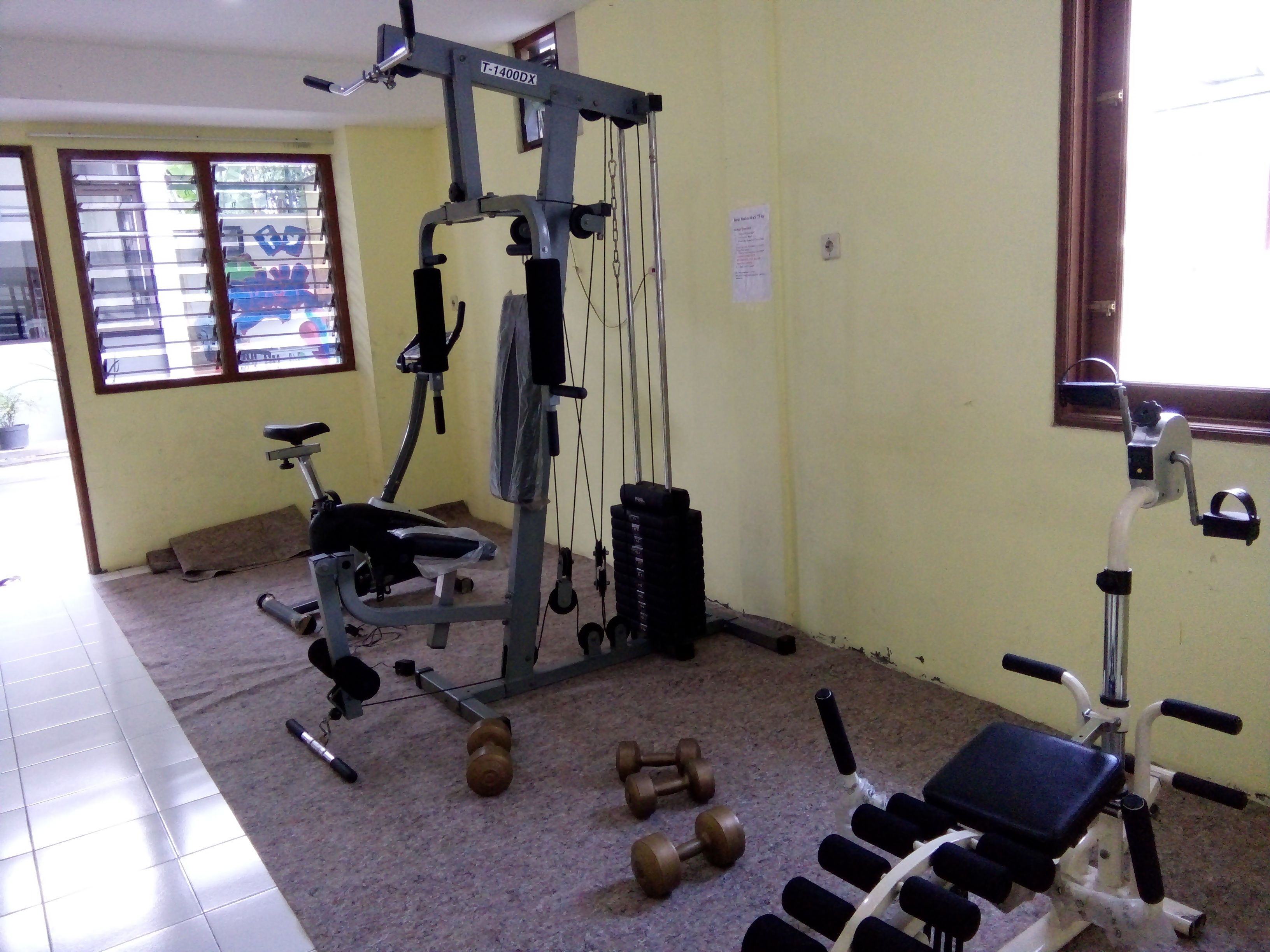 A gym with exercise equipment, including a pull-up bar, dumbbells, and a bench.