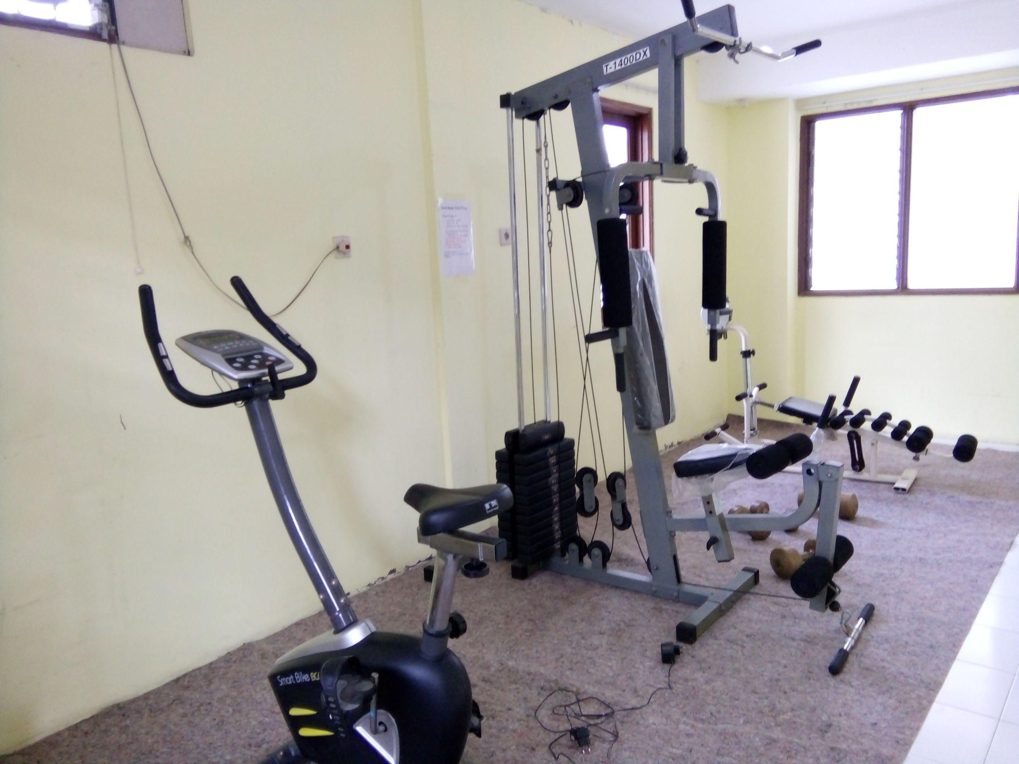Un gimnasio con equipo de ejercicio, incluyendo una elíptica, una prensa de banca y mancuernas.