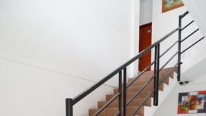 Una escalera con barandilla de metal, baldosas marrones y una planta en maceta.