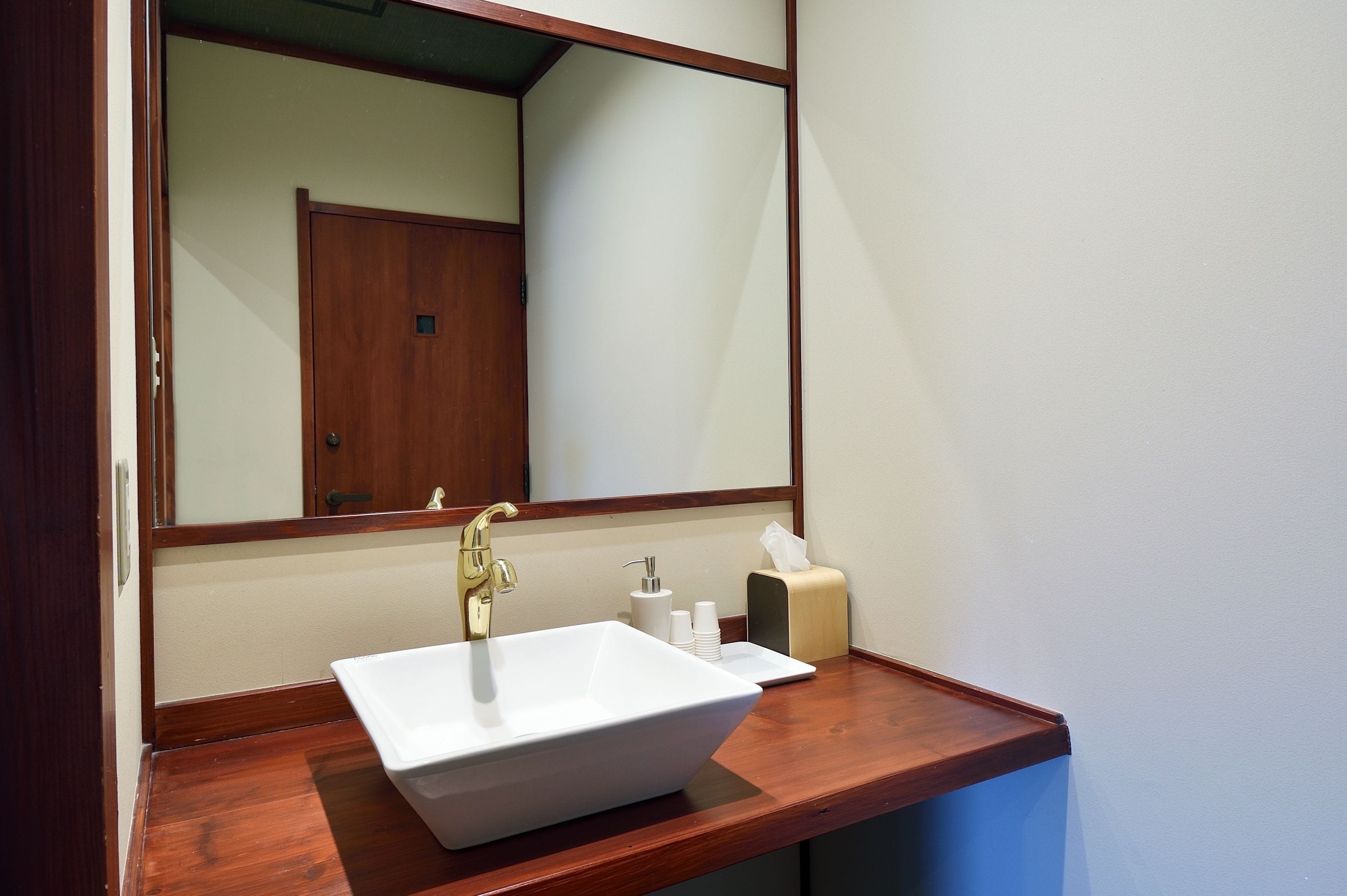 Une salle de bain avec un lavabo blanc, un miroir et un meuble-lavabo en bois.