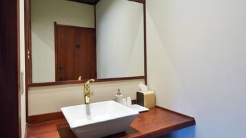 Une salle de bain avec un lavabo blanc, un miroir et un meuble-lavabo en bois.