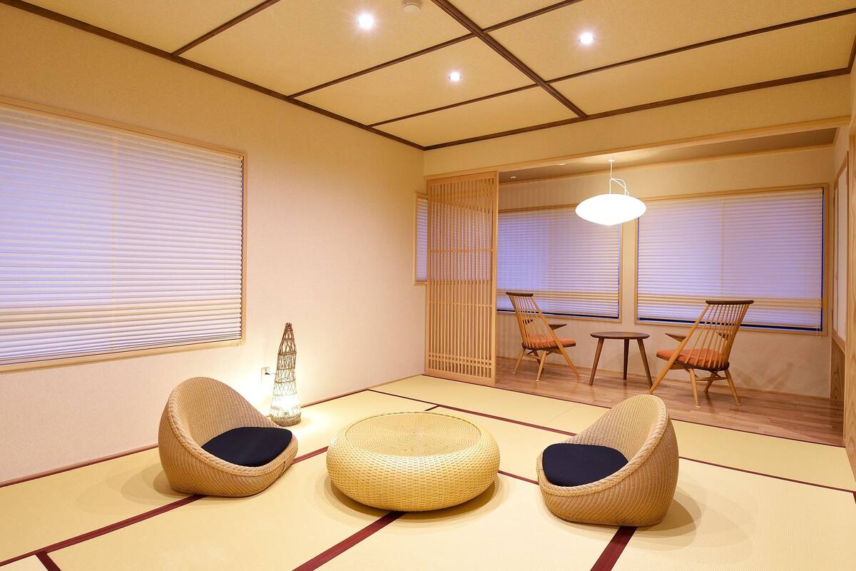 A traditional Japanese room with tatami flooring, three tatami mats, and two tatami chairs with cushions.