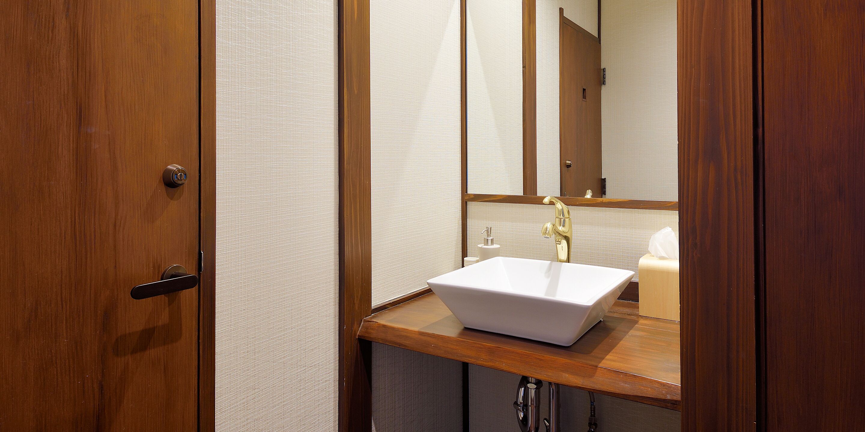 A bathroom with a wooden vanity, a white sink, and a mirror.