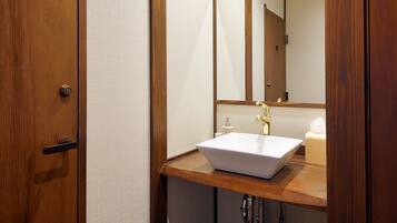 A bathroom with a wooden vanity, a white sink, and a mirror.