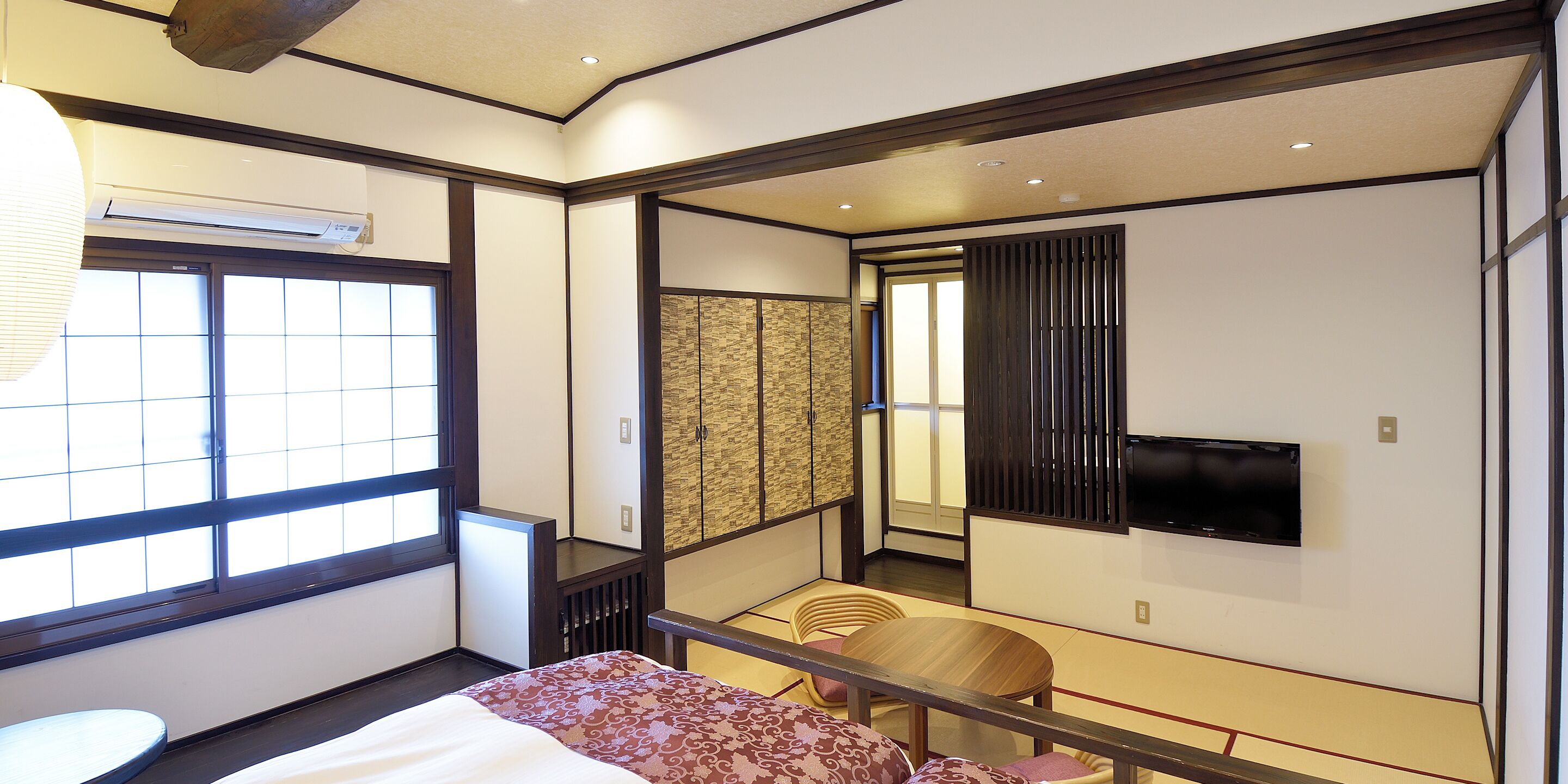 A traditional Japanese-style room with tatami flooring, a low table with cushions, and a sliding door leading to a balcony.