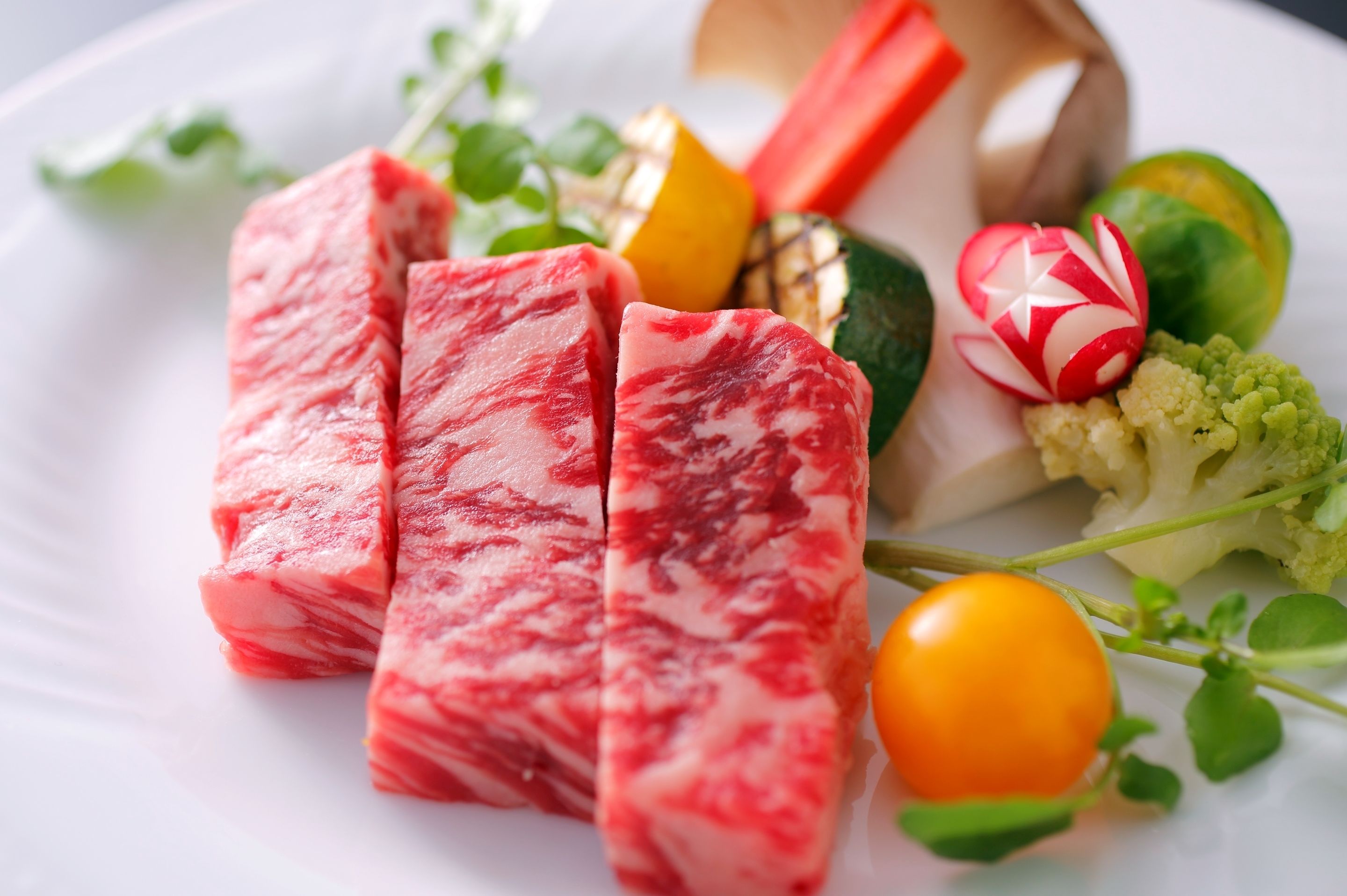 A plate with various foods including meat, vegetables, and a decorative item.