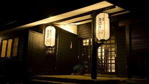 A traditional Japanese building with wooden exterior and illuminated signage. - Ryokan Okayama (Myoko)