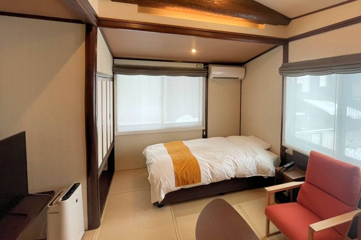 A hotel room with a bed, a desk, a chair, and a window with curtains.
