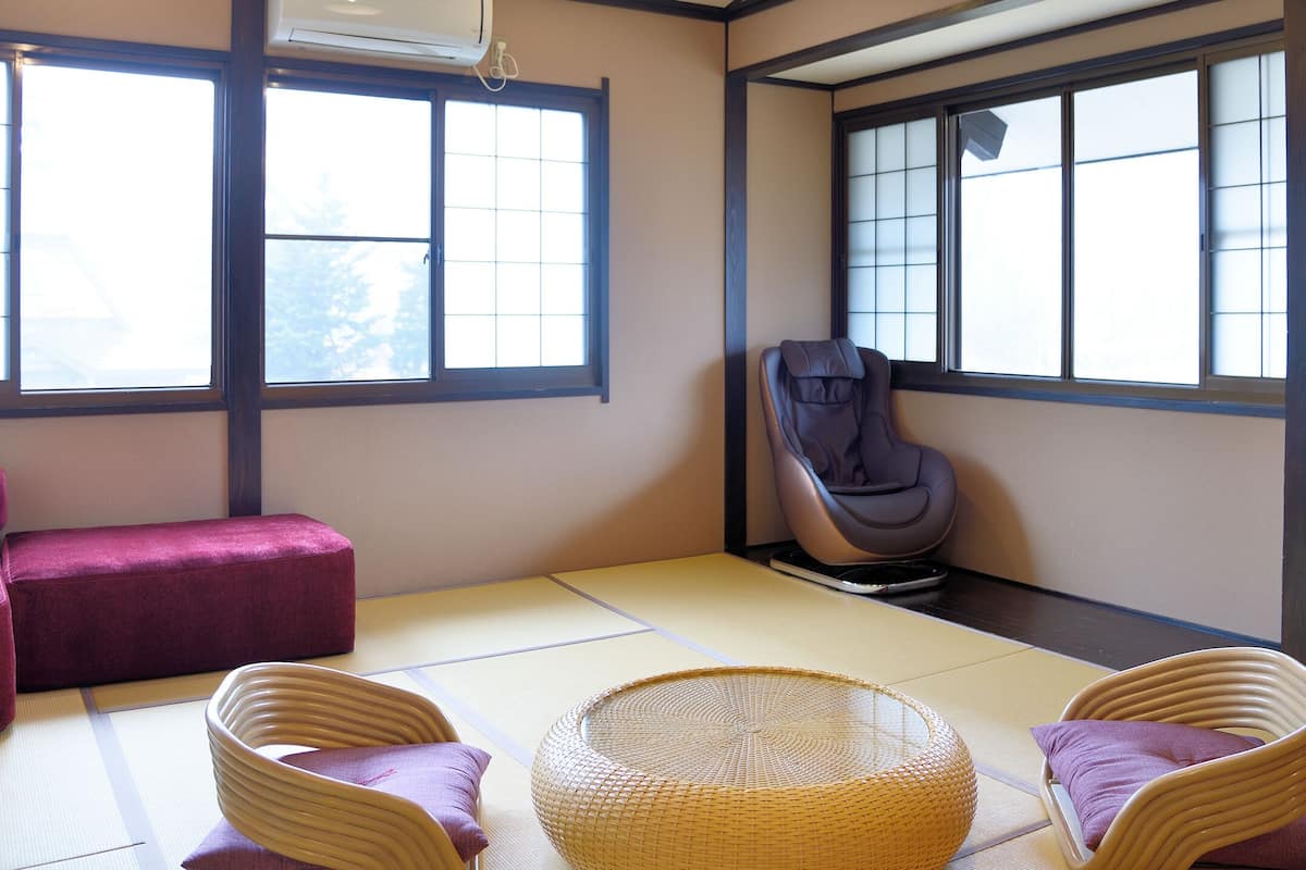 A tatami mat room with a futon, a massage chair, and a woven basket.