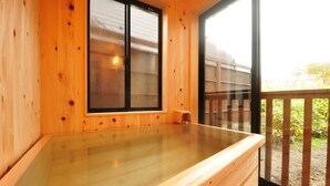 A wooden spa bath with a glass top, a window with frosted glass, and a wooden deck outside. - Ryokan Okayama (Myoko)