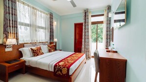 A bedroom with a bed, bedside tables, a desk, and a chair. - Rekidhiye Inn (Hithadhoo)