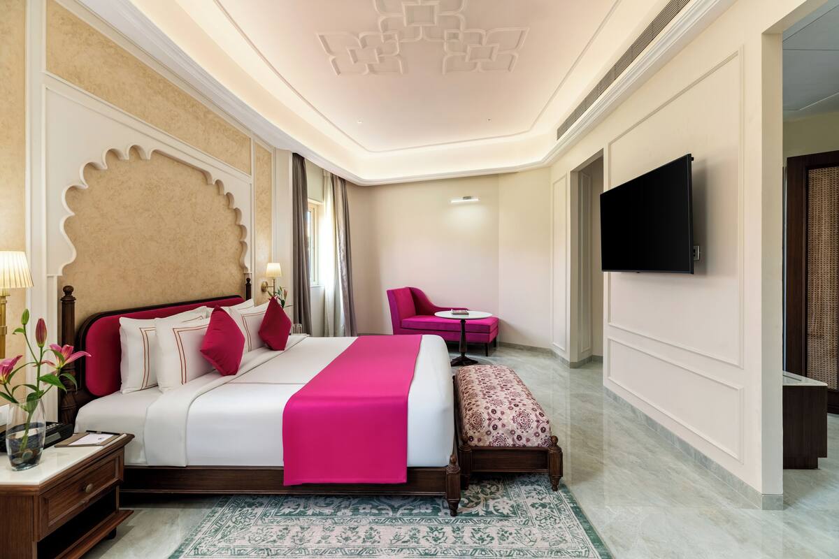 A hotel room with a large bed, a television, a small table, and a chair.