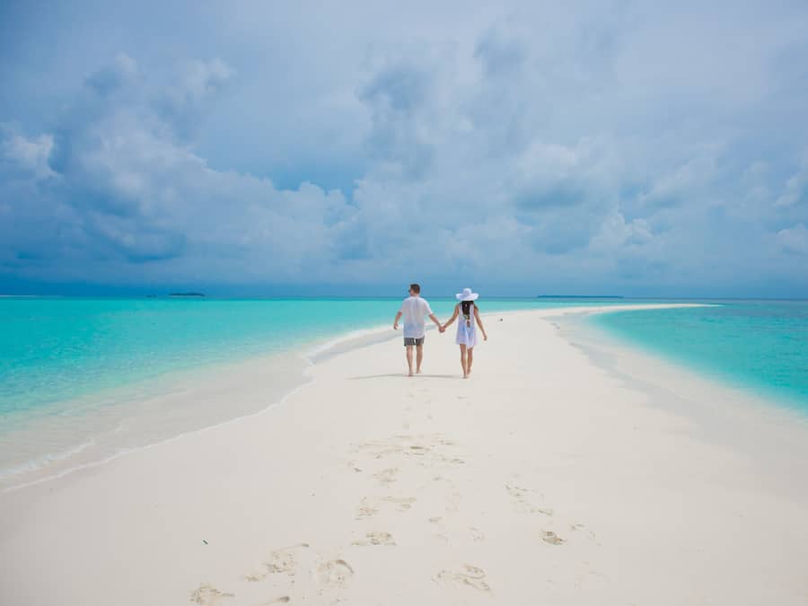 Di pantai, pasir putih, kursi berjemur, dan payung pantai