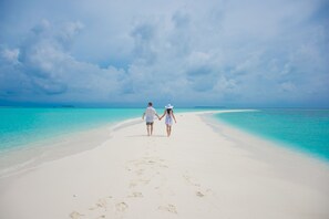 På stranden, hvit sand, solsenger og parasoller