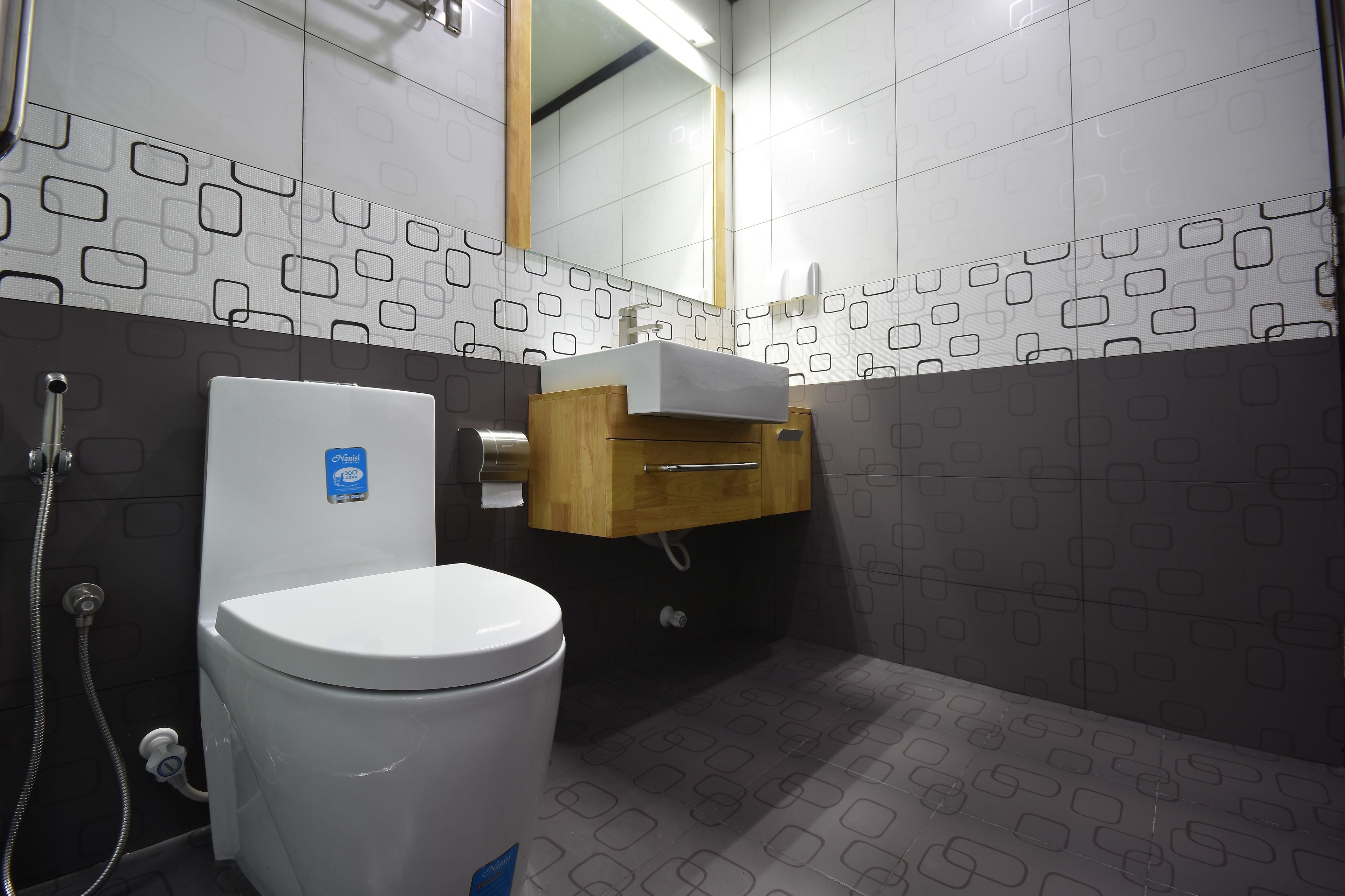 A modern bathroom with a toilet, a wooden cabinet, and patterned tiles.
