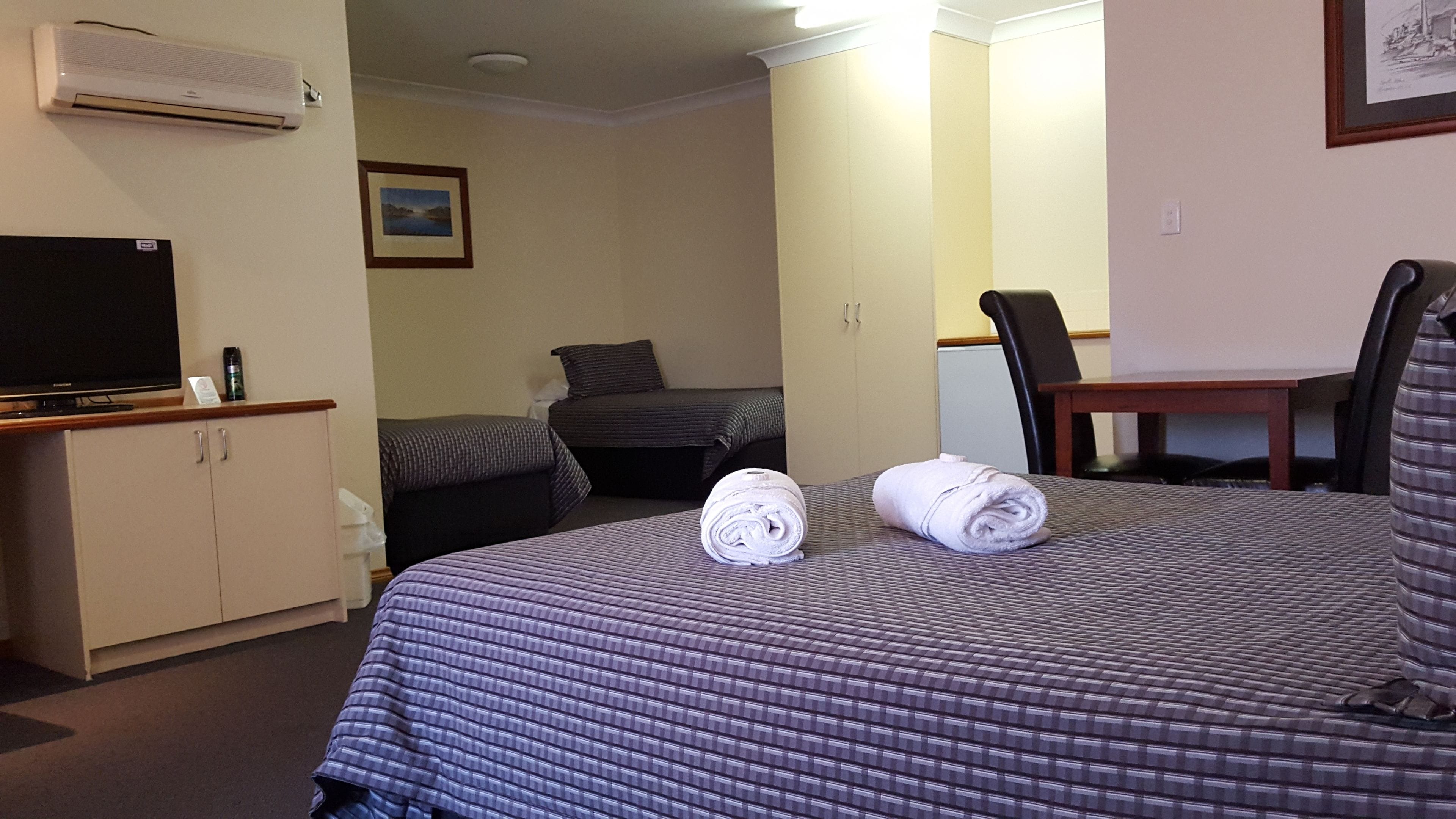 Une chambre d’hôtel avec un lit, un bureau avec une télévision, une chaise et une petite table.