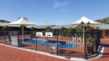 Una piscina al aire libre, sillones reclinables de piscina