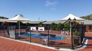 A fenced pool area with directional signs for rooms 1-7 and 8-16.