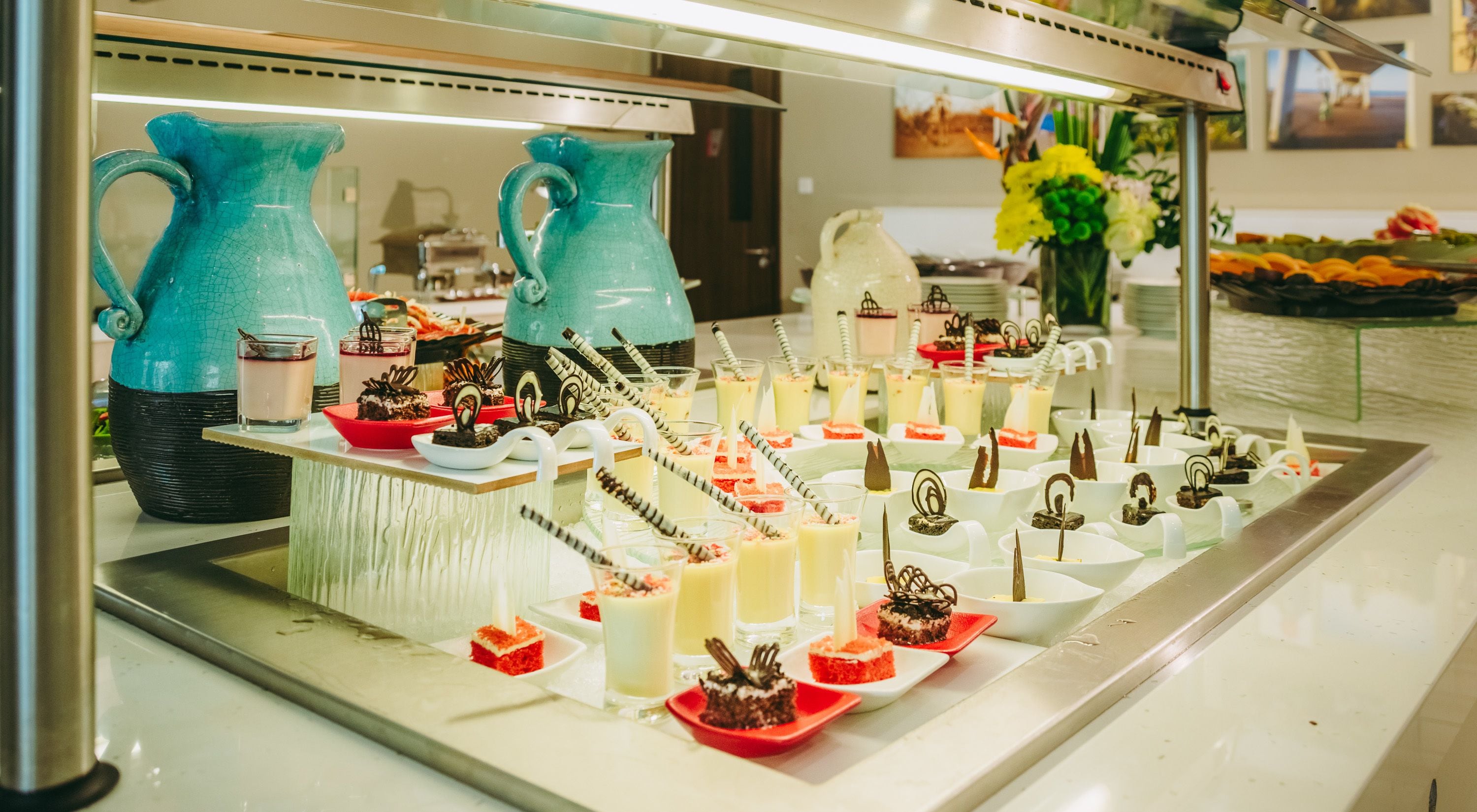 A buffet with various desserts and drinks, including cakes, cupcakes, and beverages.