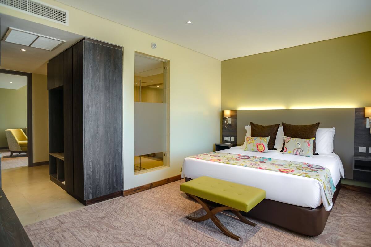 A hotel room with a bed, bench, bedside tables, and a wardrobe.