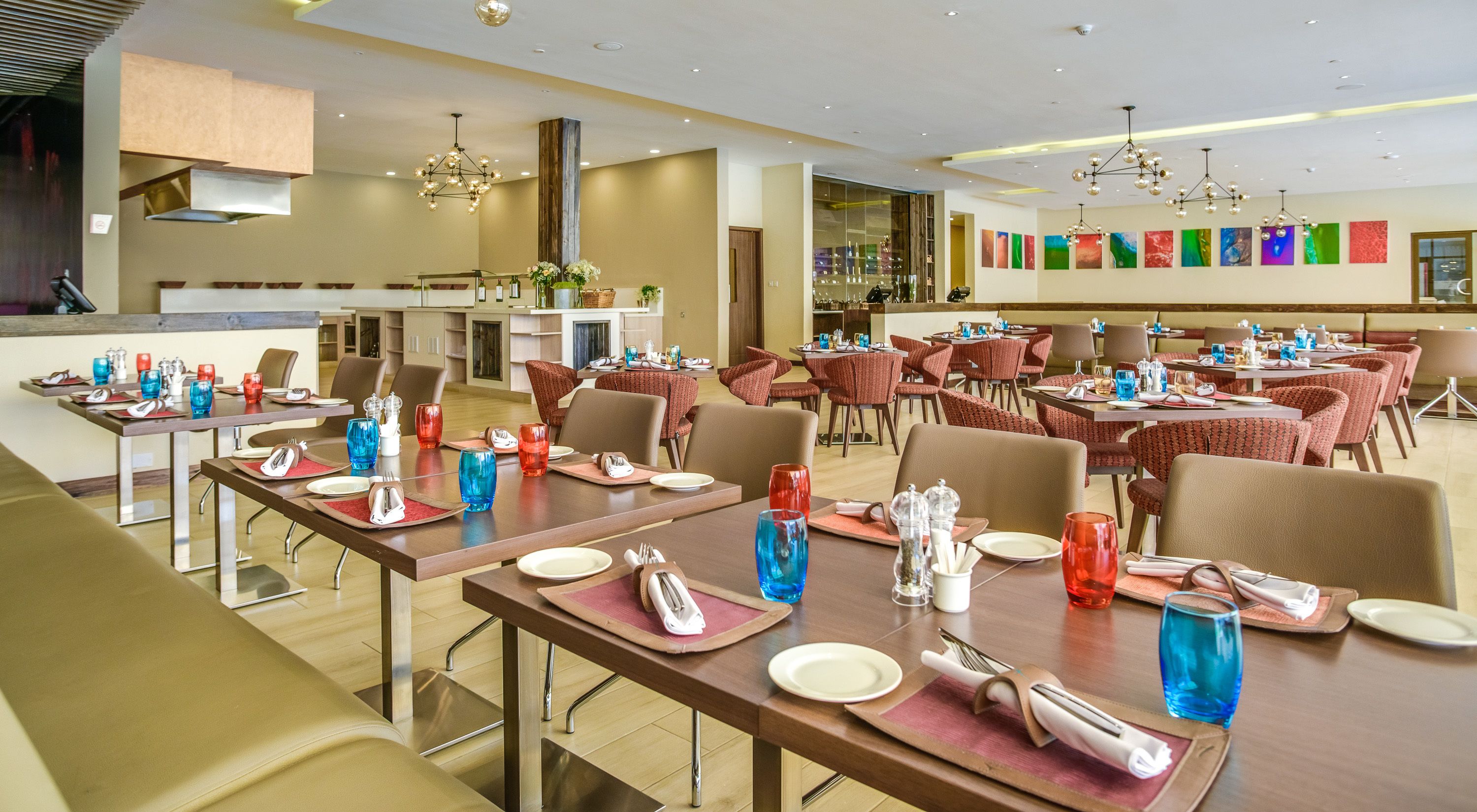 A spacious dining area with multiple tables set for guests, featuring a modern design with wooden tables and chairs.
