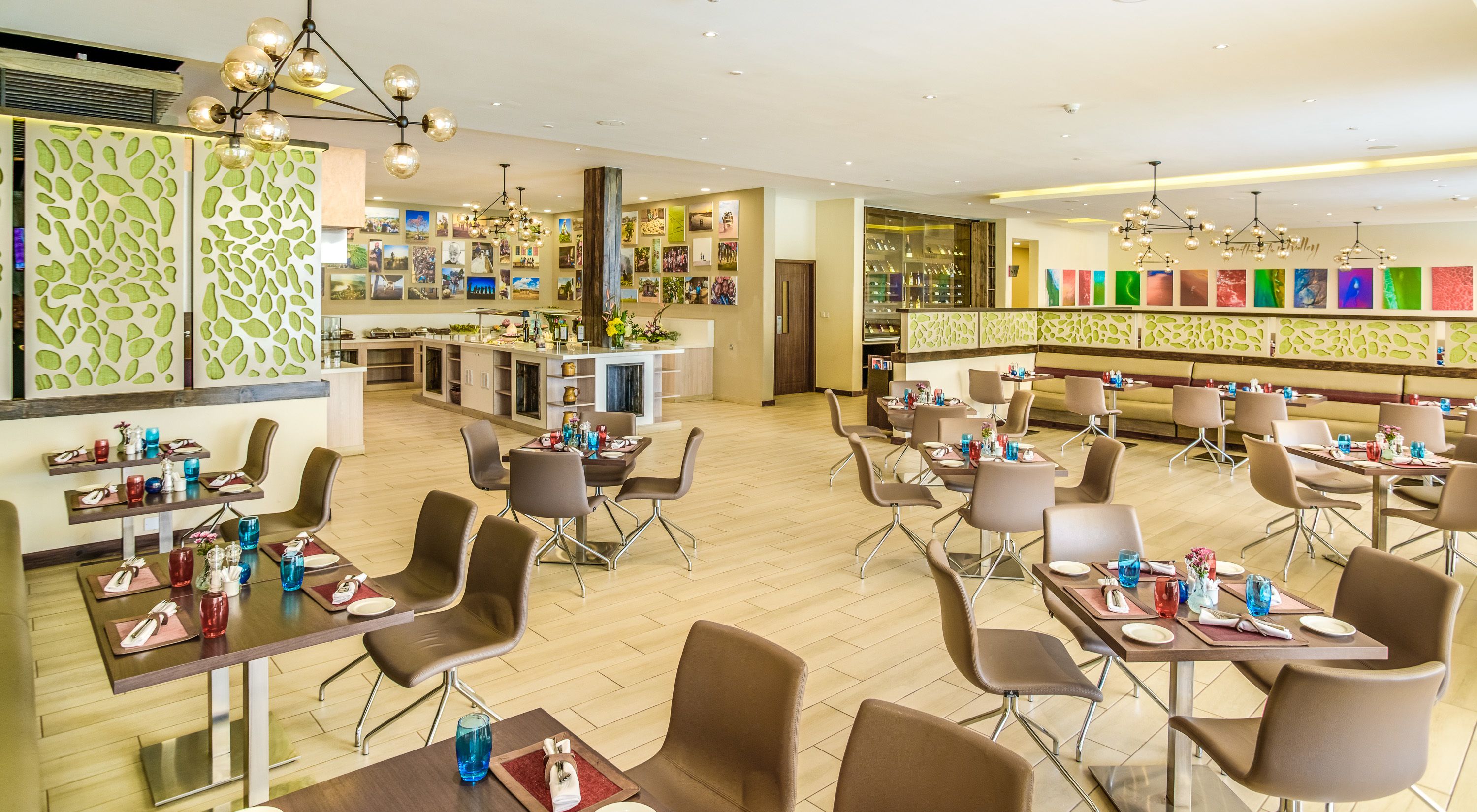 A modern restaurant with multiple dining areas, a bar, and a kitchen visible in the background.