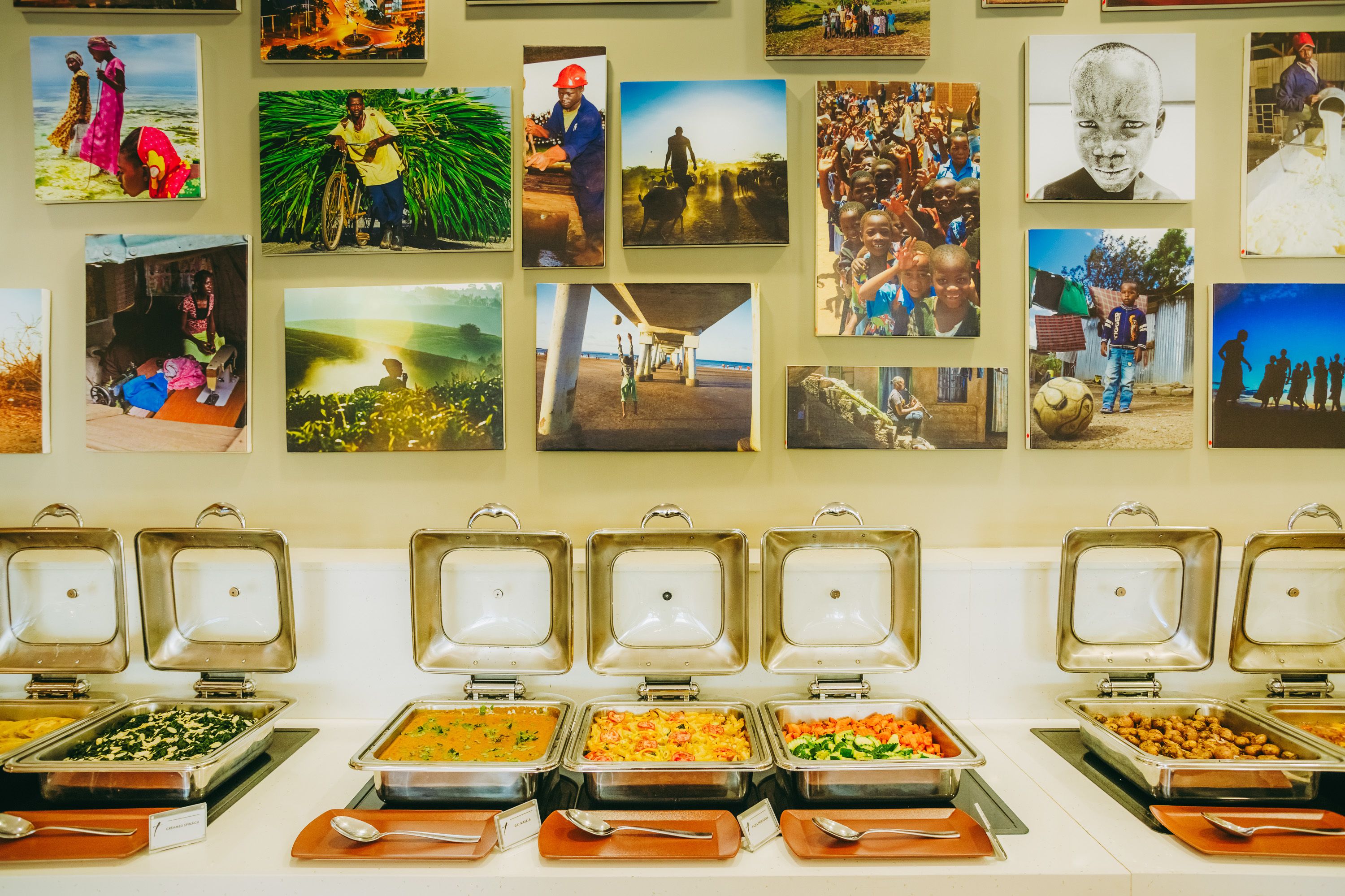 A buffet with various food options and a wall decorated with photographs.