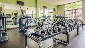 A gym with treadmills, elliptical machines, and a rack of dumbbells.