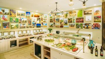 Zona de bufé con varias estaciones de comida, una amplia variedad de platos y una pared decorada con numerosas fotografías.
