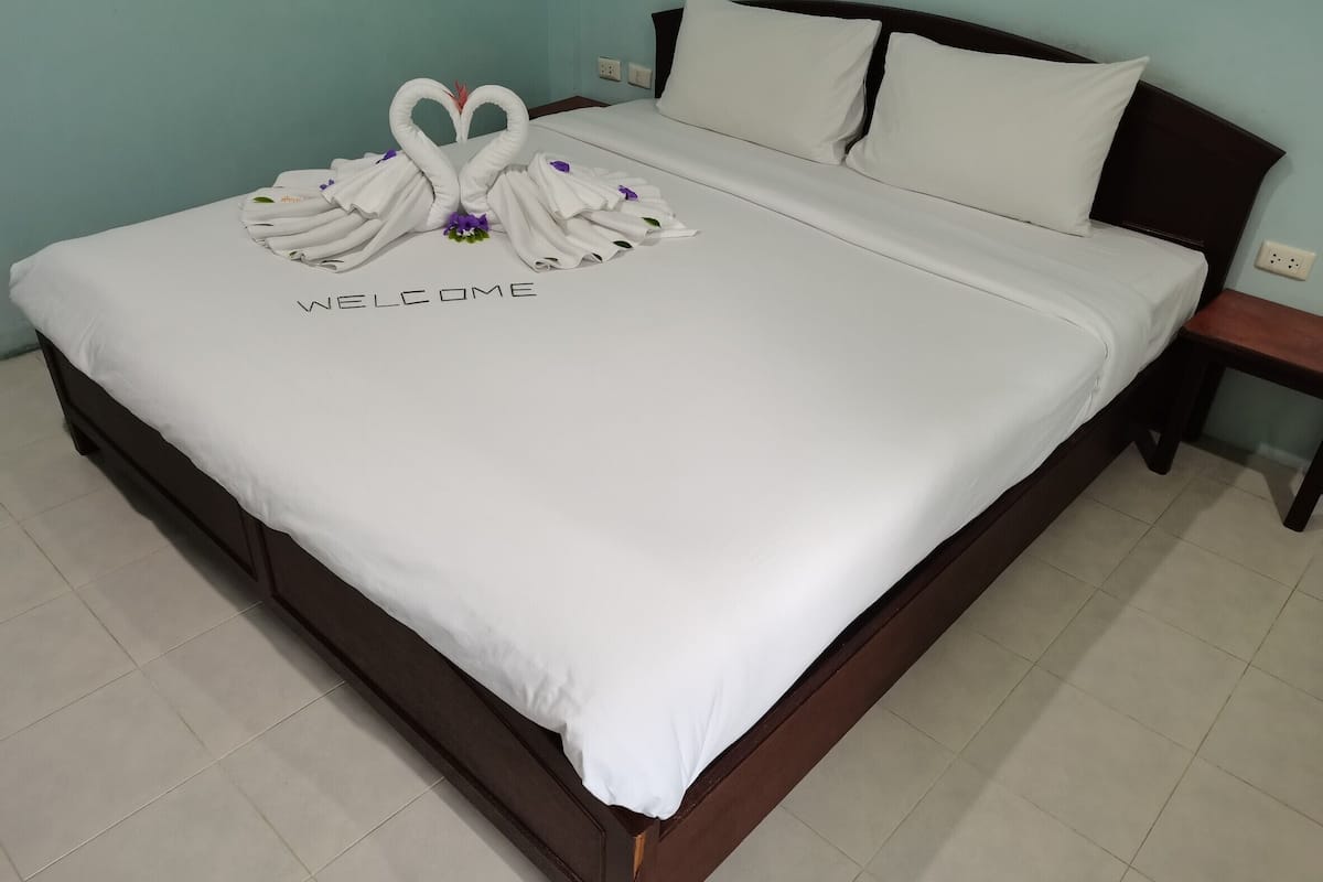 A neatly made bed with a 'WELCOME' sign and two swan-shaped towels.