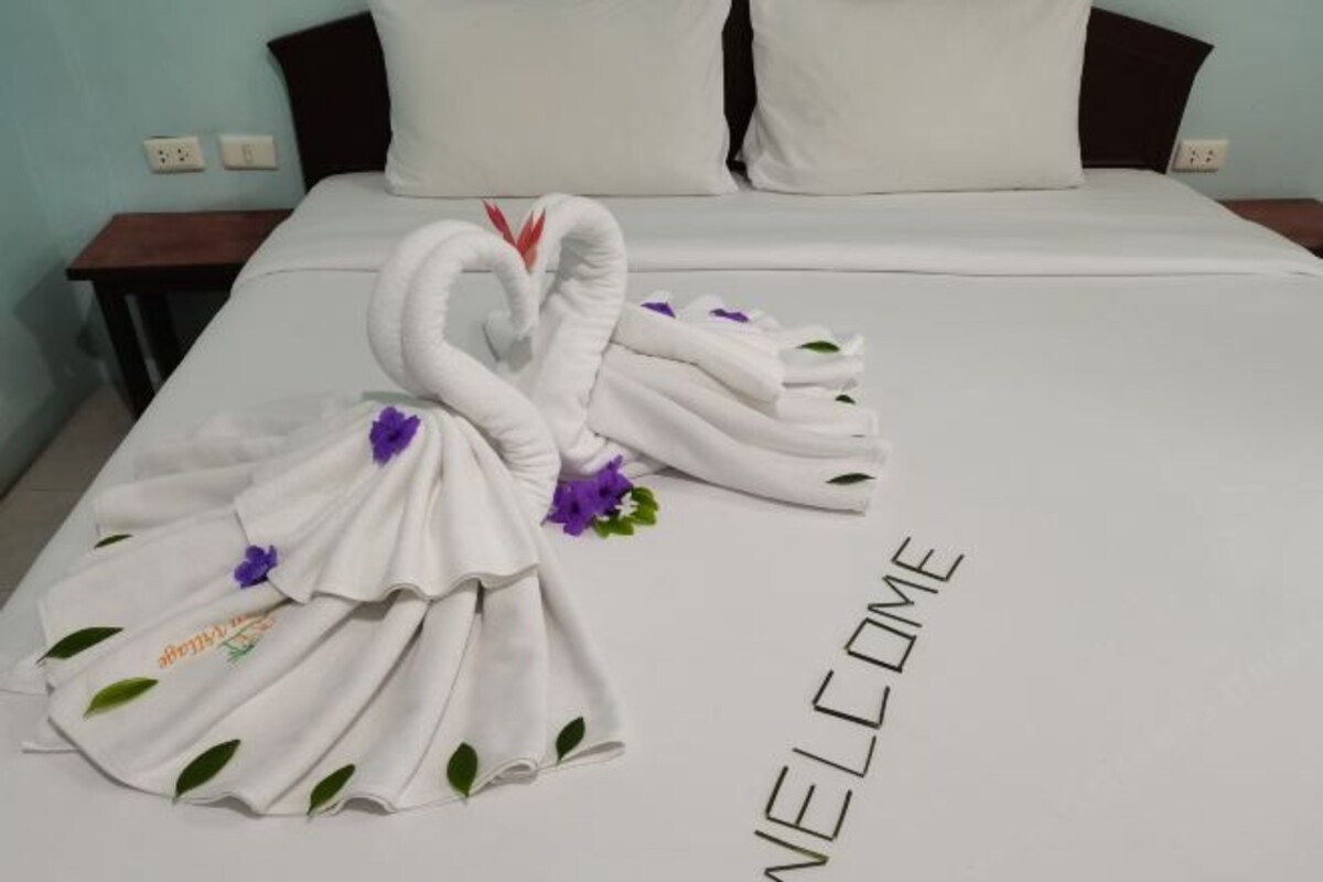 A bed with a towel arranged in the shape of a swan and the word "WELCOME" on the bedspread.