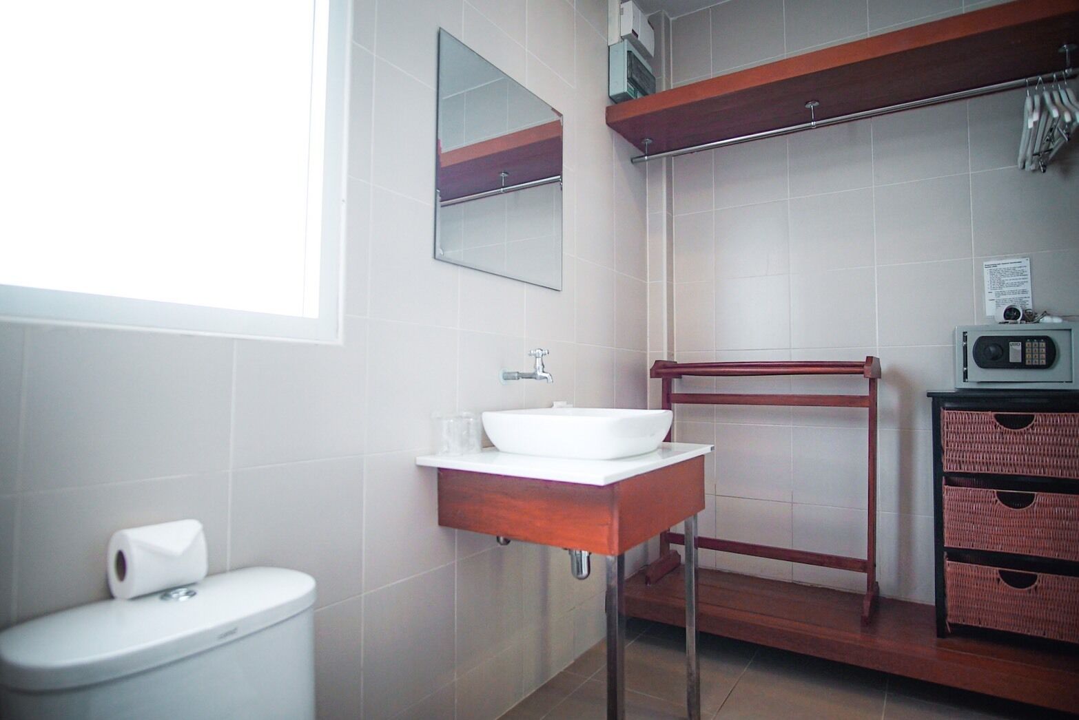 A bathroom with a white sink, a mirror, a toilet, and a shelf with baskets.